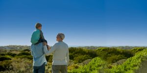 A man carrying his son on his shoulders with his father to his side